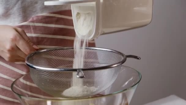 Lady pours flour through sieve over bowl for baking — Vídeos de Stock