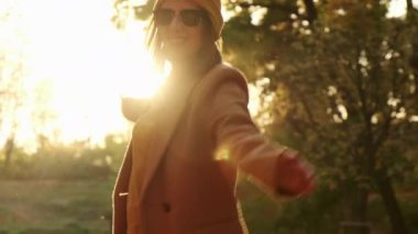 Smiling lady with glasses whirls and dances in autumn forest