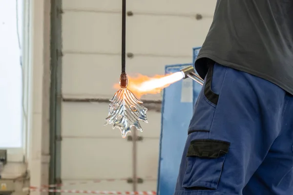 A man uses a gas burner to melt glass. A craftsman makes a glass in a leaf shaped — Stockfoto