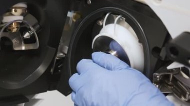 Close up analytical chemist removes the spray shield of mass spectrometer. Maintenance of LC MS qTOF 