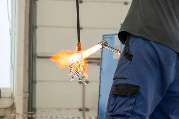 A man uses a gas burner to melt glass. A craftsman makes a glass in a leaf shaped — Stockfoto