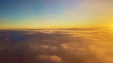 Flying into the clouds illuminated in orange by the suns rays at sunset