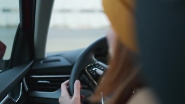 Woman driving Skoda car, hand on steering wheel, turns on the turn signal to the right, shooting from the back seat. Safety driving concept December 2021, Prague, Czech Republic.