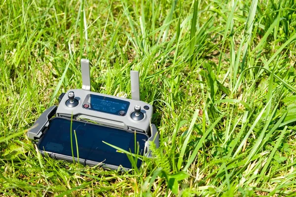 The drone console controller with the mobile phone is lying on the grass. Aerial photography of nature — Foto Stock