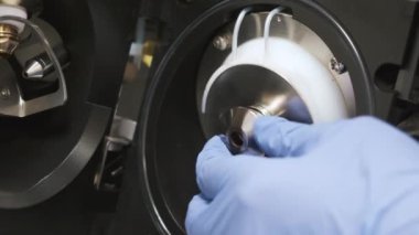 Close up analytical chemist removes the spray shield of mass spectrometer. Maintenance of LC MS qTOF 