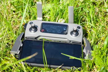 The drone console controller with the mobile phone is lying on the grass. Aerial photography of nature