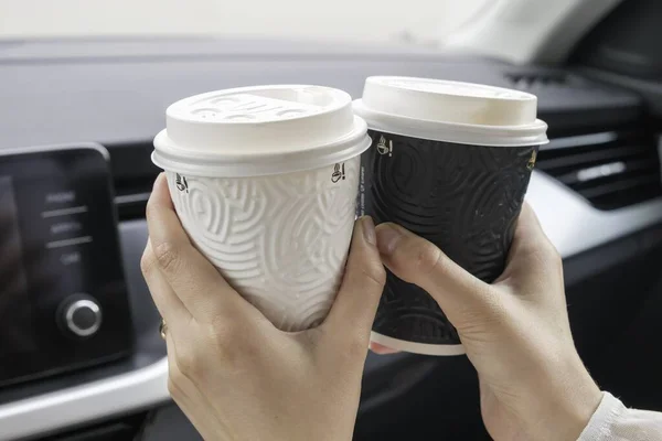 Cangkir kertas kosong dan putih dengan kopi di tangan wanita duduk di dalam mobil. Cinta dan konsep pasangan — Stok Foto