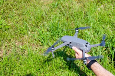 Man holding a drone before flying with green grass on the background