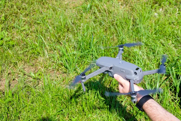 Homem segurando um drone antes de voar com grama verde no fundo — Fotografia de Stock