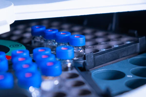 Close up vials with blue caps in the rack of auto sample for LC MS analysis. Research experiment of vaccine. Clinical analysis to detect diseases — Stockfoto
