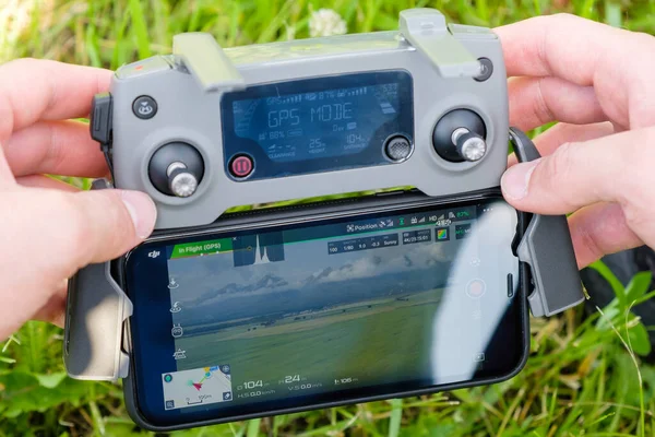 Close up the drone console controller with the mobile phone in mans hands with grass on the background. Aerial photography of nature. January 2022, Poprad, Slovakia —  Fotos de Stock