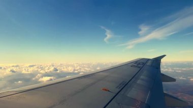 Wing of passenger airplane flying high above fluffy clouds