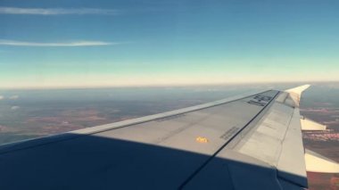 Grey wing with passenger plane number under blue sky