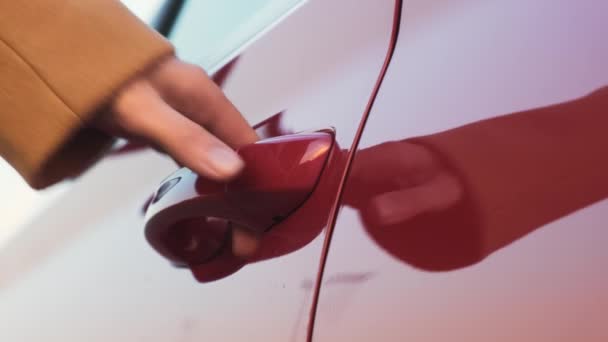 Una mujer lleva su mano a la manija roja de la puerta del coche y la abre — Vídeo de stock