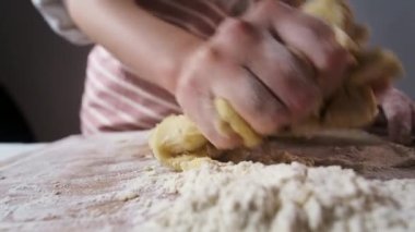 Ev hanımı tahtadan ekmek hamuru yoğurur.