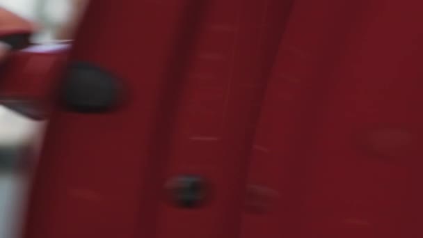 車のドアの赤いハンドルに彼女の手をもたらす女性は、それを開き、茶色のコートに座っている — ストック動画
