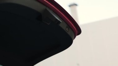 Bir kadın bagajı kapatmak için düğmeye basıyor ve kırmızı arabanın bagajı kapanıyor.