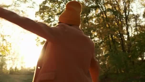 Positieve vrouw in jas en warme hoed verandert in zonnig bos — Stockvideo