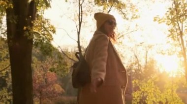 Gülümseyen kadın sonbahar parkında yolu takip etmeye davet ediyor.