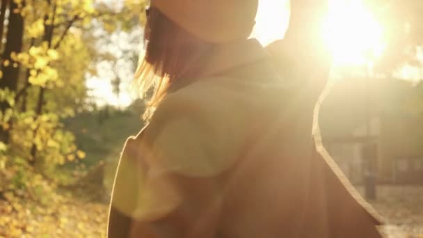 穿着外套的快乐的年轻女子在秋天的森林里转过身来 — 图库视频影像