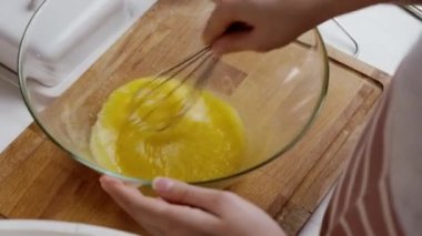 Kadın çırpılmış yumurta ve şekerden sıvı çırpıyor.