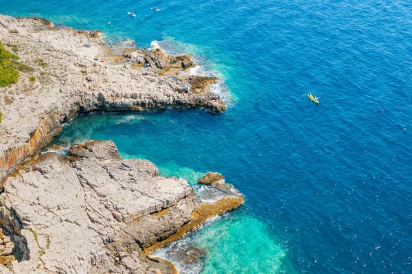 Top uitzicht op sporters of toeristen kajakken in het turkoois transparant blauw water van Adriatische zee rotsachtige kust — Stockfoto