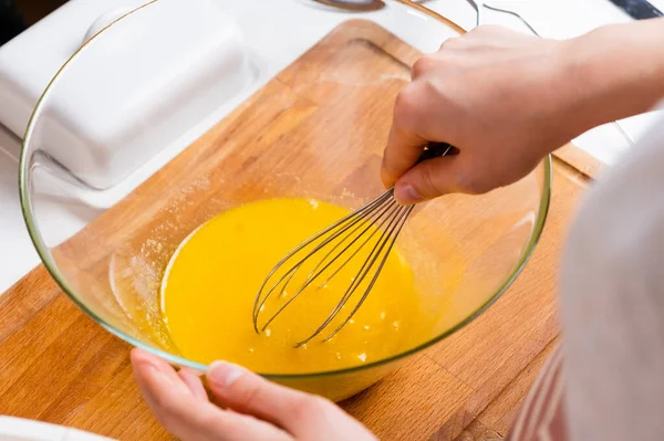 Primo piano di mani di donne che montano uova per fare la pasta sulla scrivania di legno in cucina. Cucina casalinga — Foto Stock
