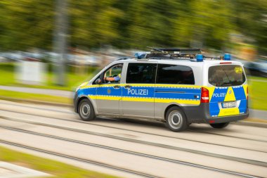  Polis, elinde mektuplar olan Alman polis arabasıyla sokaklarda hızlı araba kullanıyor. Bulanık caddede polis arabası aceleyle ilerliyor. Ocak 2022, Dresden, Almanya