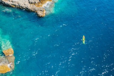 Adriyatik 'in kayalık kıyılarının şeffaf mavi sularında kayak yapan sporcu veya turistlerin en iyi manzarası