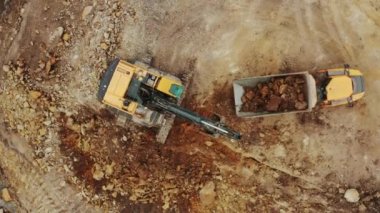 Üstteki sarı kazıcı açık çukurdan mineralleri alıp kamyona yüklüyor.