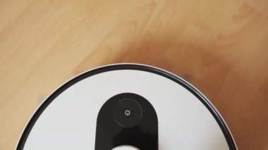 Beyaz bir elektrikli süpürge, ahşap zeminde çalışır. Evin temizliği kolaydı..