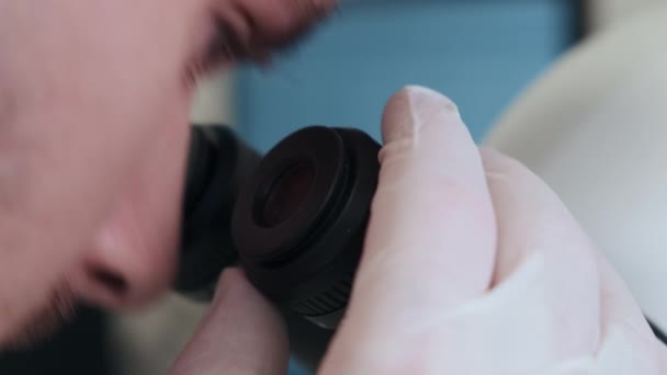 Jeune scientifique qui regarde au microscope dans un laboratoire. Le chimiste ajuste le microscope, puis examine les échantillons. Recherche dans le laboratoire moderne — Video