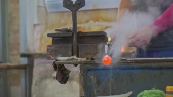 Glass blower shaping a bubble of melted glass on a rod. Glass manufacturing process. Production of glass bottles or vases. — Stock Video