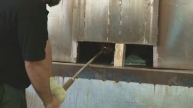 Tamirci soğutma odasında yeni bir vazo tutuyor. El yapımı cam üretimi 