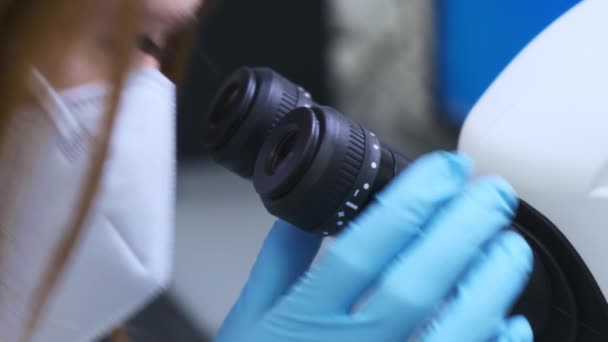 Jovem cientista olhando através de um microscópio em um laboratório. Químico ajusta microscópio e, em seguida, examina amostras. Pesquisa no laboratório moderno — Vídeo de Stock