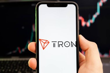 TRON TRX kripto para birimi logosu erkek eliyle akıllı telefon ekranında ve yeşil arkaplanda artan bir eğilimle birlikte 