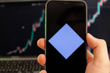 Akıllı telefon ekranındaki kripto para birimi logosu yeşil arka plandaki grafikte giderek artan bir eğilim gösteriyor. 
