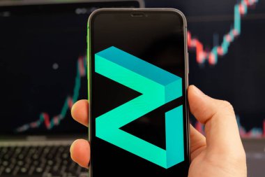 Zilliqa ZIL şifreleme logosu erkek eliyle akıllı telefon ekranında ve yeşil arka planda artan bir eğilimle birlikte 