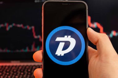 Şifreli para piyasası analizinin DigiByte DGB uygulaması insan eliyle cep telefonu ekranında ve iniş trendleri grafiklerinde arka planda, Şubat 2022, San Francisco, ABD