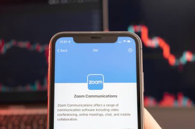 Zoom Communications hisse senedi fiyatları, arka planda eğilim çizgisi grafik bar tablosu ile ticaret piyasasında azalır. Şirket logosu olan bir cep telefonu taşıyan adam, Şubat 2022, San Francisco, ABD