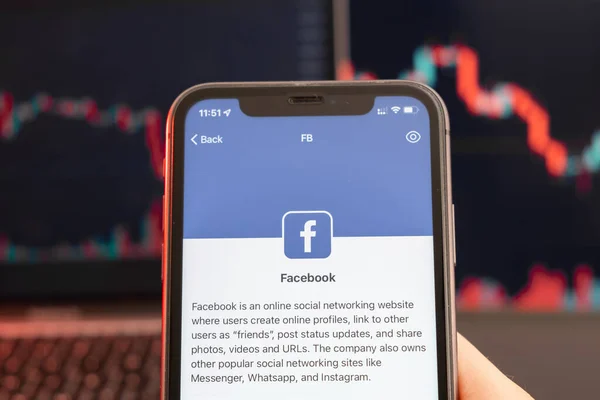 Diminuição do preço das ações do Facebook no mercado de negociação com gráfico de barras gráfico de linha de tendência de baixa em segundo plano. Homem segurando um telefone celular com logotipo da empresa, fevereiro de 2022, San Francisco, EUA — Fotografia de Stock