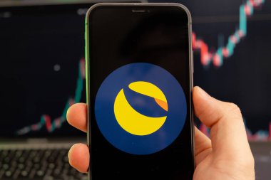 Terra LUNA kripto para birimi logosu erkek eliyle akıllı telefon ekranında ve yeşil arka planda büyüyen bir eğilimle birlikte 