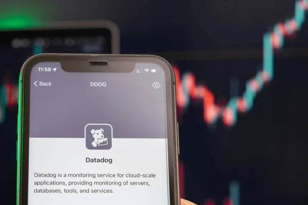Datadog Aktienkurs Aufwärtstrend mit Diagrammen auf dem Hintergrund. Männliche Hände halten ein Smartphone mit Logo auf dem Bildschirm, Februar 2022, San Francisco, USA — Stockfoto