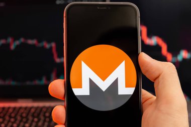 Monero XMR hisse senedi piyasa analizi insan eliyle cep telefonu ekranında ve iniş trendleri grafiklerinde arka planda, Şubat 2022, San Francisco, ABD