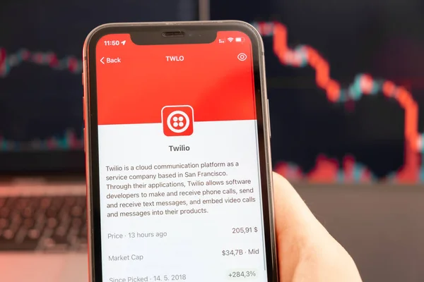 Twilio tendência de queda do preço das ações com gráficos vermelhos em segundo plano. Mãos de homem segurando um smartphone com logotipo na tela, fevereiro de 2022, San Francisco, EUA — Fotografia de Stock