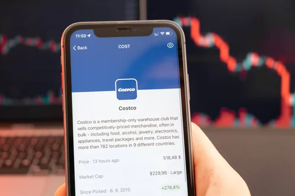 Costso Aktienkurs Abwärtstrend mit roten Graphen auf dem Hintergrund. Männliche Hände halten ein Smartphone mit Logo auf dem Bildschirm, Februar 2022, San Francisco, USA — Stockfoto