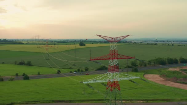 Linie dystrybucji energii i wieża koronkowa na polu o zachodzie słońca — Wideo stockowe