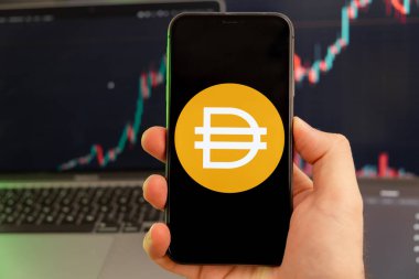 Akıllı telefon ekranındaki Dai kripto para birimi logosu yeşil arka planda büyüyen bir eğilimle birlikte erkek elinde. 