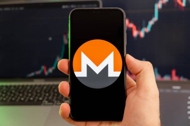 Monero XMR hisse senedi pazar analizi uygulaması insan eliyle cep telefonu ekranında ve büyüyen grafikler arka planda, Şubat 2022, San Francisco, ABD