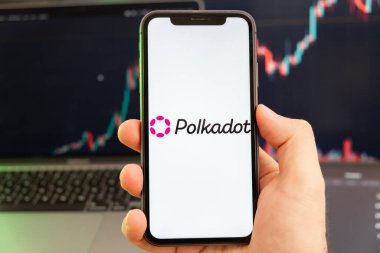 Polkadot DOT kripto para birimi logosu erkek eliyle akıllı telefon ekranında ve yeşil arka planda giderek artan bir eğilim var 